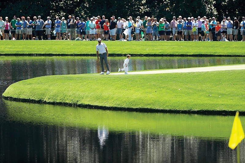 In this April 10, 2019, file photo, Dustin Johnson and his son, Tatum, stand on the ninth green during the par-3 tournament at the Masters in Augusta, Ga. The Par 3 Contest will not be played at the spectator-free Masters in November.