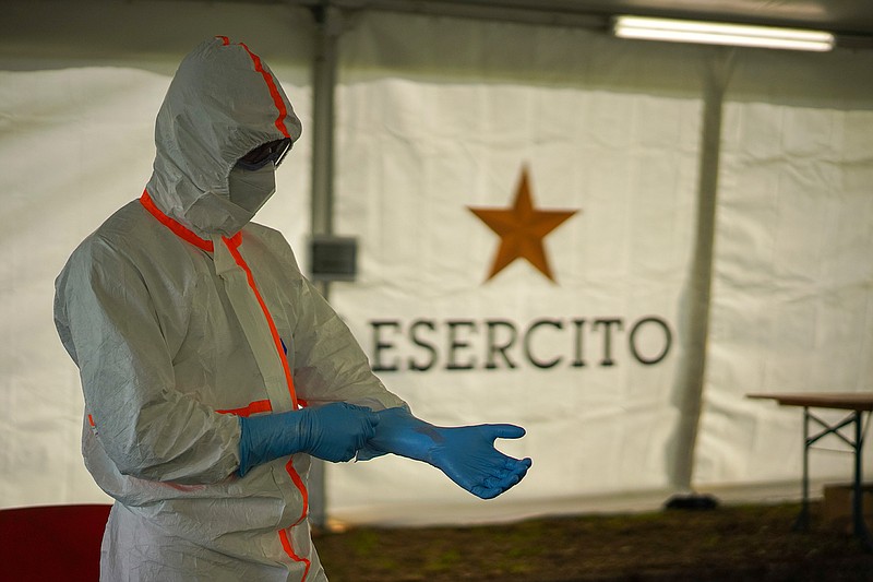 A medical staffer gets ready to perform swabs to test for coronavirus, in the Military barracks of Cecchignola in Rome, Tuesday, Oct. 27, 2020. As Italy faces a new wave of COVID-19 infections, the Italian military is helping healthcare services in the effort to contain infection. Defense minister Lorenzo Guerini has signed an agreement with the Ministry of Health Ministery to provide temporary drive-through structures in to perform nose and throat swabs  to increase the daily Covid-19 testing capacity of the country.  (AP Photo/Andrew Medichini)