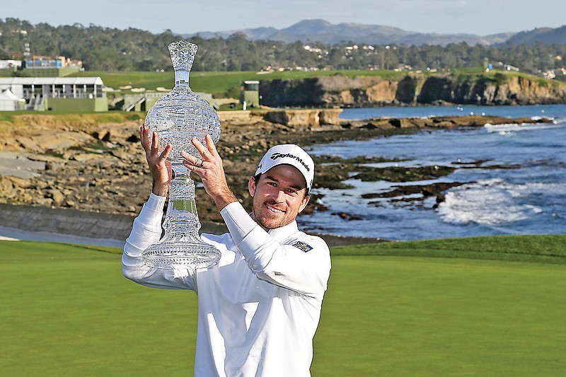 In this Feb. 9 file photo, Nick Taylor holds up his trophy on the 18th green of the Pebble Beach Golf Links after winning the AT&T Pebble Beach National Pro-Am in Pebble Beach, Calif. The win got him into his first Masters, but Taylor will miss out on the roars without spectators.