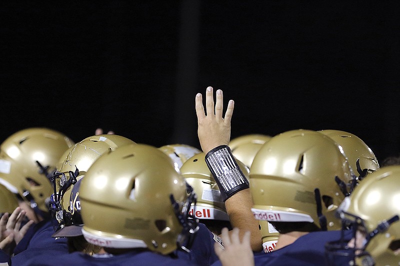 A Helias player raises four fingers in the huddle to signify the beginning of the fourth quarter of a game this season against Rock Bridge at Ray Hentges Stadium.