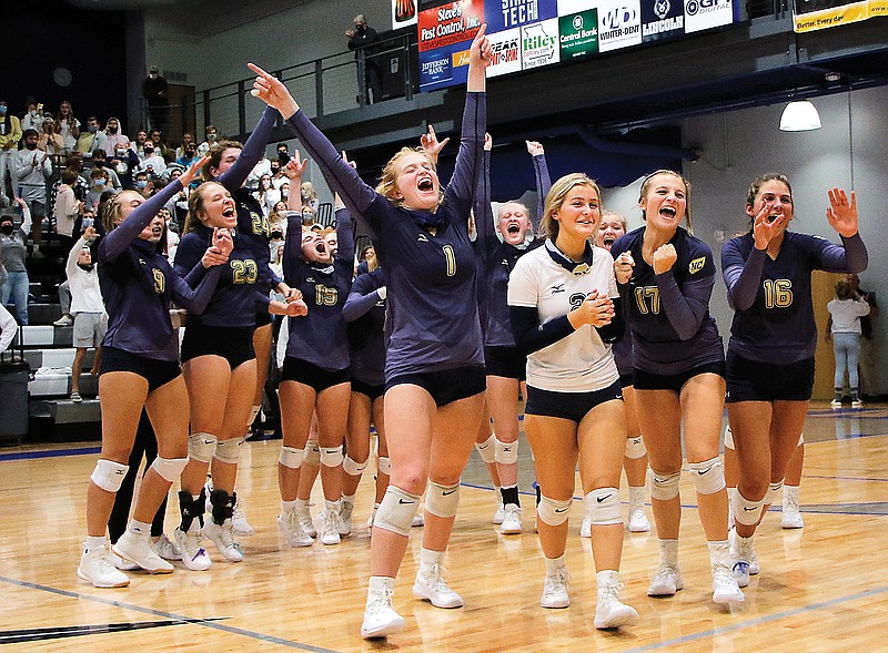 The Helias volleyball team yells in celebration as seniors (from left) Cate Albertson, Lacey Heidbrink, Ella Randolph and Grace Wilding walk to receive the plaque after winning the Class 5 District 9 Tournament title Thursday night at Capital City High School.