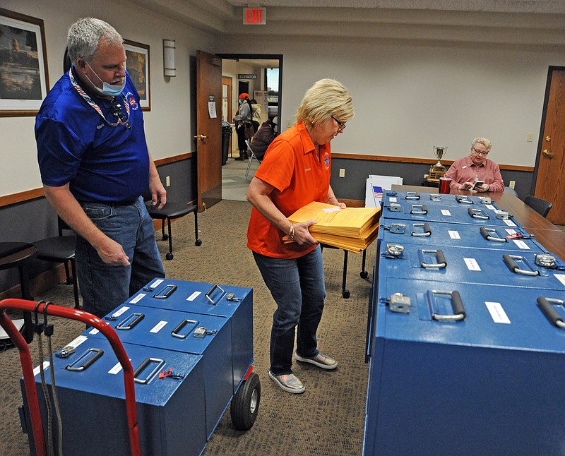 Cole County Clerk Steve Korsmeyer, left, and Penny Quigg, right, Chairman of the Cole County Republican Central Committee, watch Lynn Reinkemeyer, center, Deputy Clerk, as she removes absentee ballots from one of several locked absentee ballot boxes inside the Cole County Annex Building. Shaun Zimmerman / News Tribune photo