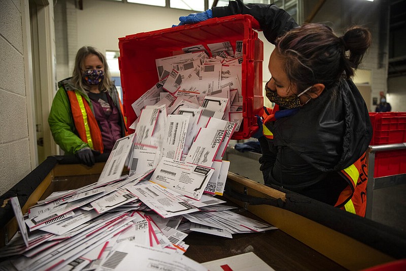 Election worker Kristen Mun from Portland empties ballots from a ballot box at the Multnomah County Elections Division, Tuesday, Nov. 3, 3030 in Portland, Ore. Oregon is the first state in the nation to institute voting by mail and automatic voter registration. (AP Photo/Paula Bronstein)