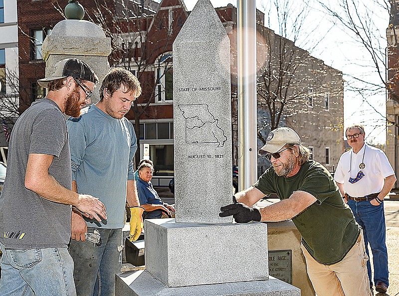 In the background stands Cole County Presiding Commissioner Sam Bushman, who watches Thursday as Kevin McClary, right, and employees Brandon Ballew, left, and Dillon Jackson install the Cole County Bicentennial marker on courthouse grounds. McClary owns Missouri River Monument Co. in Boonville and was contracted to construct, etch and install the monument.