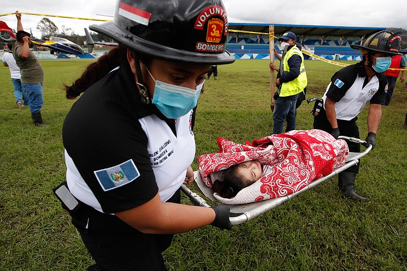 A girl rescued from the zone where residents are believed buried by a massive, rain-fueled landslide, is carried on a stretcher to a waiting ambulance during a search and rescue operation, in San Cristobal Verapaz, Saturday, Nov. 7, 2020, in the aftermath of Tropical Storm Eta. (AP Photo/Moises Castillo)