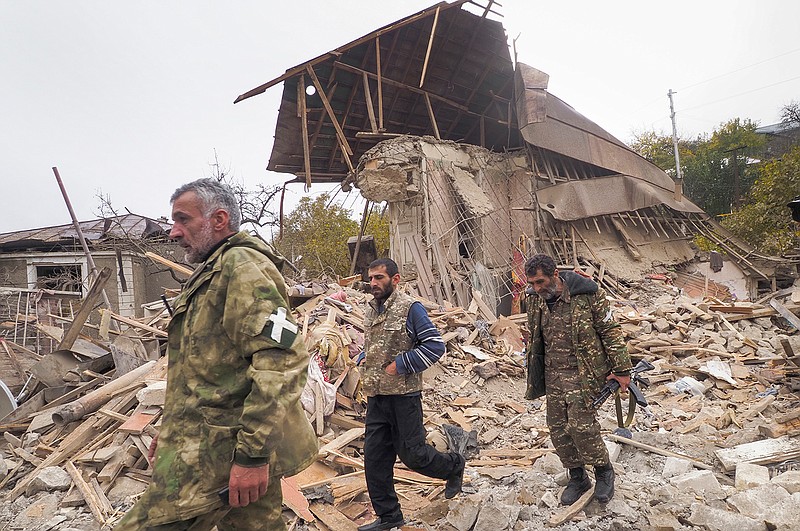 Ethnic Armenian soldiers walk past a house destroyed by shelling by Azerbaijan's artillery in Stepanakert, the separatist region of Nagorno-Karabakh, Friday, Nov. 6, 2020. Nagorno-Karabakh authorities said that three civilians were killed by Azerbaijani shelling of the regional capital, Stepanakert on Friday. (AP Photo)