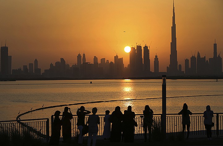 In this Oct. 7, 2016 file photo, people watch the sunset over the skyline, with Burj Khalifa at right, in Dubai, United Arab Emirates. The United Arab Emirates announced on Saturday a major overhaul of the country's Islamic personal laws, allowing unmarried couples to cohabitate, loosening alcohol restrictions and criminalizing so-called "honor killings." (AP Photo/Kamran Jebreili, File)