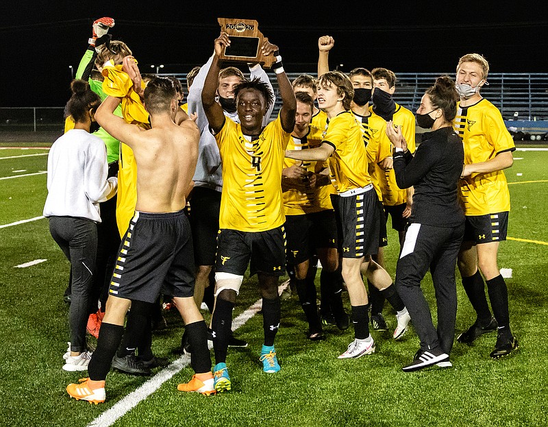 Fulton senior midfielder Clement Mahoro holds aloft the District 6 championship trophy plaque while celebrating with his teammates after the Hornets' 3-2 win against the Moberly Spartans last Thursday night at Moberly. Fulton (16-6) hosts Pleasant Hill (15-4-2) in a Class 2 state quarterfinal game at 6 p.m. today.