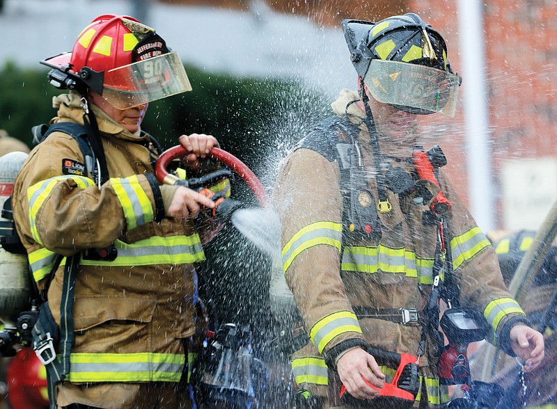 Jefferson City firefighters wash each other off with water after responding to a structure fire on Franklin Street on Monday. There were no injuries, and no one was in the house at the time of the fire, which took about ten minutes to put out. JCFD Public Information Officer Jason Turner said there was serious damage throughout the building. 
