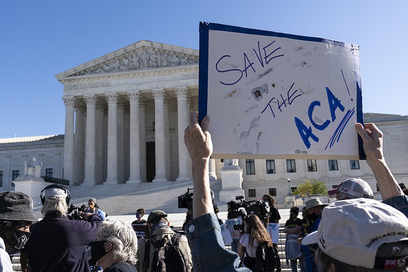 A demonstrator holds a sign in front of the U.S. Supreme Court as arguments are heard about the Affordable Care Act, Tuesday, Nov. 10, 2020, in Washington. (AP Photo/Alex Brandon)