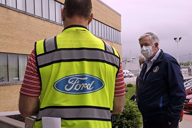 FILE - Missouri Gov. Mike Parson talks to a Ford representative outside Ford's Kansas City Assembly Plant in Claycomo, Mo., in this Friday, May 15, 2020, file photo. (AP Photo/Charlie Riedel, File)