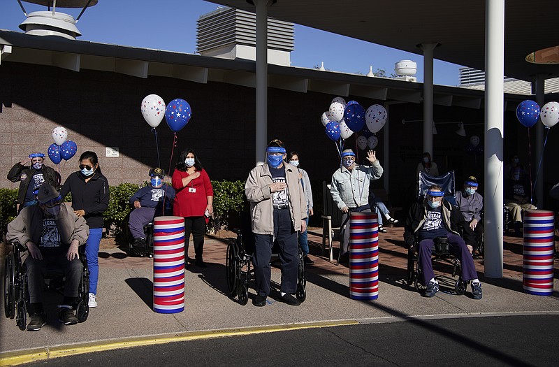 Residents and staff listen to the national anthem during a socially-distanced Veterans Day ceremony at the Southern Nevada State Veterans Home, Wednesday, Nov. 11, 2020, in Boulder City, Nev. The special outdoor ceremony was held with face coverings and distancing as a precaution against the coronavirus. (AP Photo/John Locher)