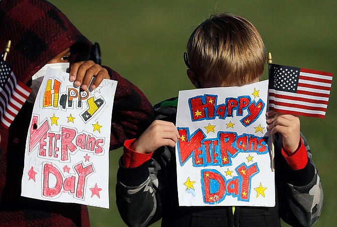 Cedar Hill Elementary School students shyly hold up hand-colored signs to wish veterans a happy Veterans Day during a parade Wednesday. The school usually holds a special Veterans Day assembly but was forced to get creative and figure out a way to honor veterans that allowed for better social distancing.
