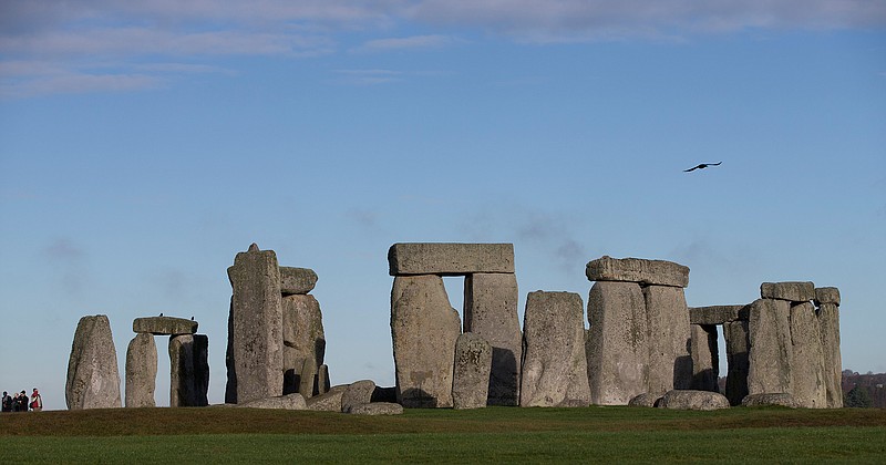 In this Tuesday, Dec. 17, 2013 file photo, visitors take photographs of the world heritage site of Stonehenge, England. The British government went against the recommendations of planning officials when it gave its consent Thursday Nov. 12, 2020, to controversial plans for a road tunnel to be built near the prehistoric monument of Stonehenge in southern England in order to ease congestion along a stretch widely prone to gridlock. (AP Photo/Alastair Grant, File)