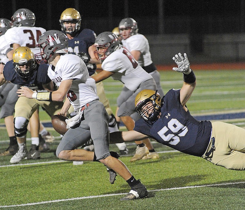 Jacob Watson of Helias dives to knock the ball out of the hands of Nevada's Kaden Denney during last Friday night's game at Ray Hentges Stadium.