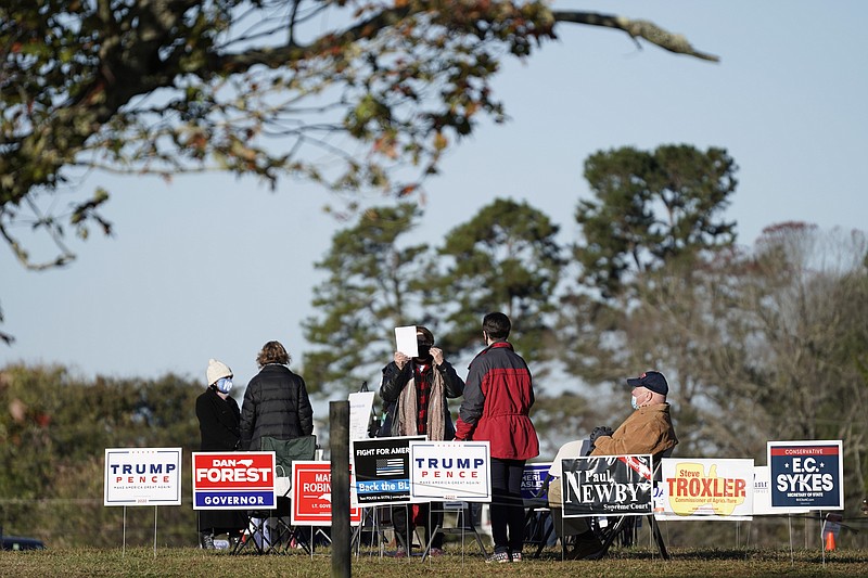 Polling workers assist voters on a brisk fall morning at the Efland Ruritan Club polling site in Efland, N.C., Tuesday, Nov. 3, 2020. (AP Photo/Gerry Broome)