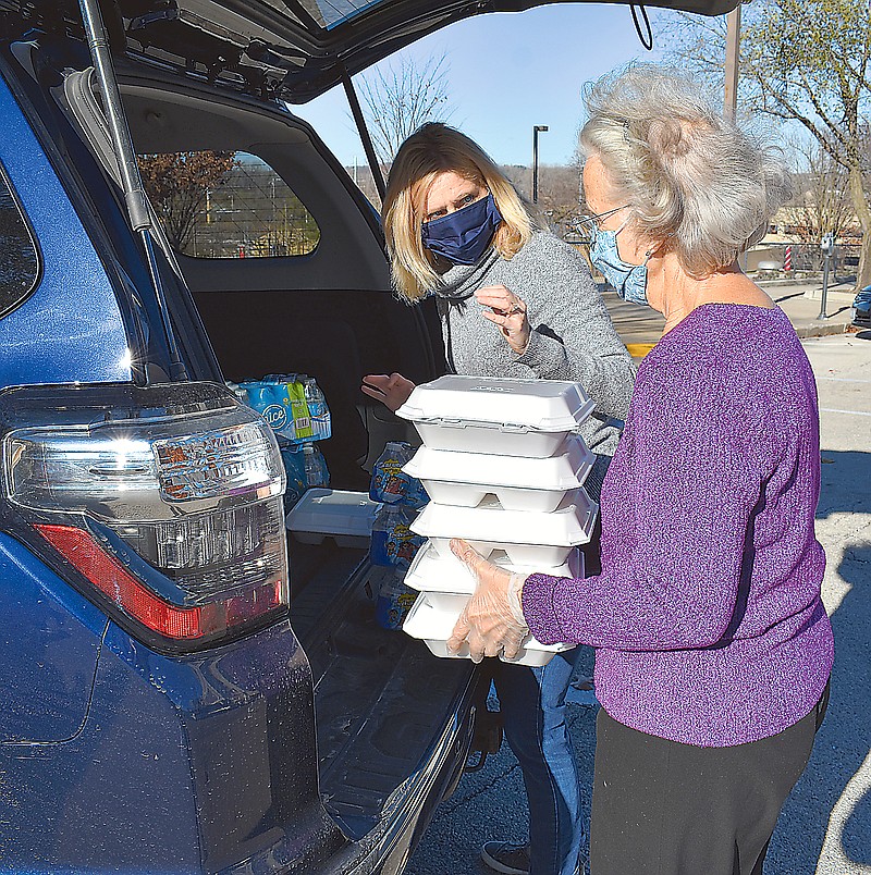 Nancy Schmidt, left, takes a stack of meals from Janet Kremer to load into her vehicle on Sunday's World Day of the Poor event organized by St. Peter Catholic Church. The church gave away a total of 320 meals at four locations in town.