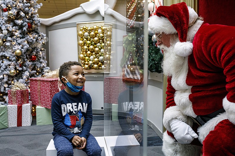 Kashden Dunlap, of Enola, visits with Santa Claus, with safety protocols in place, at Capital City Mall in Lower Allen Township,  Pa., on Wednesday, Nov. 11, 2020.  Malls are doing all they can to keep the jolly old man safe from the coronavirus, including banning kids from sitting on his knee, completely changing what a Santa visit looks like.  (Dan Gleiter/The Patriot-News via AP)