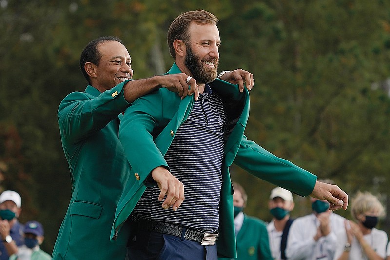 Tiger Woods helps Dustin Johnson with his green jacket after his victory Sunday at the Masters in Augusta, Ga.