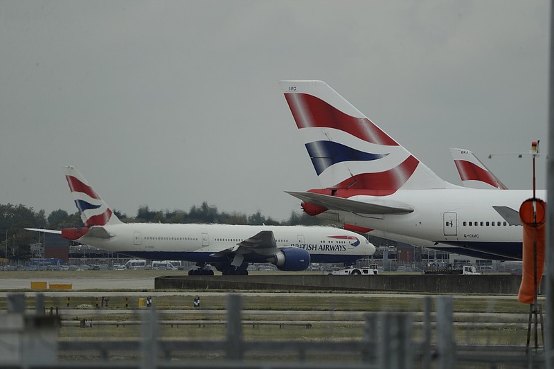 FILE - In this Monday, Sept. 9, 2019 file photo, a British Airways plane, at left, is towed past other planes sitting parked at Heathrow Airport in London. British Airways said Tuesday Nov. 17, 2020, that it will start testing passengers flying from the U.S. to London’s Heathrow Airport for COVID-19 in an effort to persuade the British government it should scrap rules requiring most international travelers to quarantine for 14 days. (AP Photo/Matt Dunham, File)