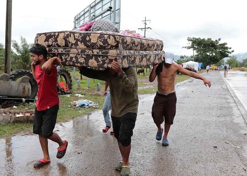 Neighbors help each other as they evacuate the area before Hurricane Iota makes landfall in San Manuel Cortes, Honduras, Monday, November 16, 2020. Hurricane Iota rapidly strengthened into a Category 5 storm that is likely to bring catastrophic damage to the same part of Central America already battered by a powerful Hurricane Eta less than two weeks ago. (AP Photo/Delmer Martinez)