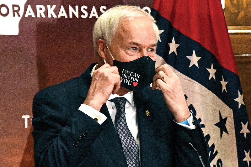 Gov. Asa Hutchinson removes his mask before a briefing at the state capitol Monday' July 2020 in Little Rock. (Staci Vandagriff/The Arkansas Democrat-Gazette via AP)