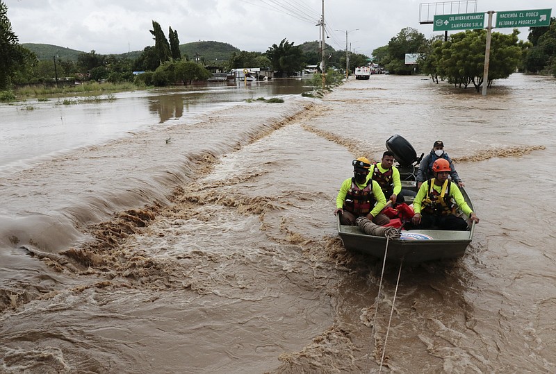Rescuers navigate a flooded road in a boat after the passing of Hurricane Iota in La Lima, Honduras, Wednesday, Nov. 18, 2020. Iota flooded stretches of Honduras still underwater from Hurricane Eta, after it hit Nicaragua Monday evening as a Category 4 hurricane and weakened as it moved across Central America, dissipating over El Salvador early Wednesday. (AP Photo/Delmer Martinez)