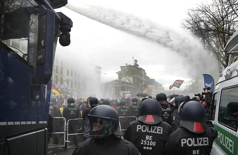 Police uses water canons to clear a blocked a road between the Brandenburg Gate and the Reichstag building, home of the German federal parliament, as people attend a protest rally in front of the Brandenburg Gate in Berlin, Germany, Wednesday, Nov. 18, 2020 against the coronavirus restrictions in Germany. Police in Berlin have requested thousands of reinforcements from other parts of Germany to cope with planned protests by people opposed to coronavirus restrictions. (AP Photo/Michael Sohn)