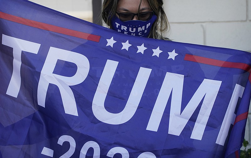 A supporter of President Donald Trump holds a flag during a news conference Tuesday, Nov. 17, 2020, in Las Vegas. (AP Photo/John Locher)
