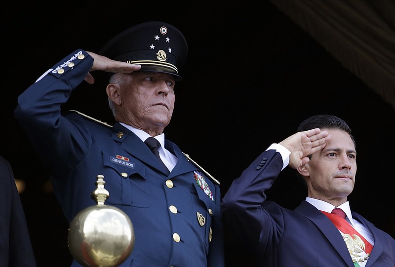 FILE - In this Sept. 16, 2016 file photo, Defense Secretary Gen. Salvador Cienfuegos, left, and Mexico's President Enrique Pena Nieto, salute during the annual Independence Day military parade in Mexico City's main square. U.S. prosecutors on Wednesday, Nov. 18, 2020, formally dropped a drug trafficking and money laundering case against Gen. Cienfuegos, a decision that came after Mexico threatened to cut off cooperation with U.S. authorities unless the general was sent home. (AP Photo/Rebecca Blackwell, File)