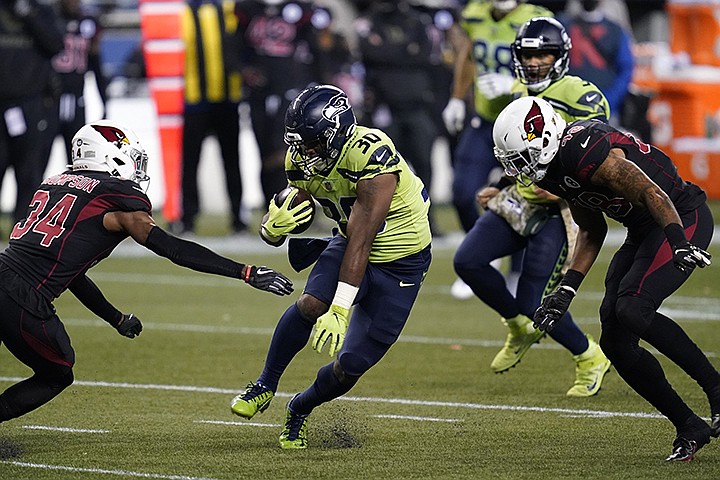 Seattle Seahawks running back Carlos Hyde (30) rushes as Arizona Cardinals free safety Jalen Thompson (34) attempts the tackle during the first half of an NFL football game, Thursday, Nov. 19, 2020, in Seattle. (AP Photo/Elaine Thompson)