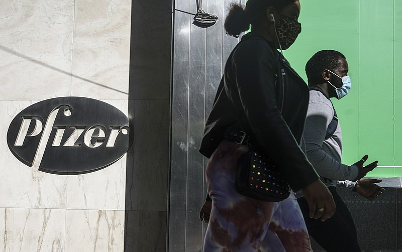 FILE - In this Nov. 9, 2020, file photo, pedestrians walk past Pfizer world headquarters in New York. Pfizer said Friday, Nov. 20, 2020, it is asking U.S. regulators to allow emergency use of its COVID-19 vaccine, starting the clock on a process that could bring limited first shots as early as next month and eventually an end to the pandemic -- but not until after a long, hard winter. (AP Photo/Bebeto Matthews, File)
