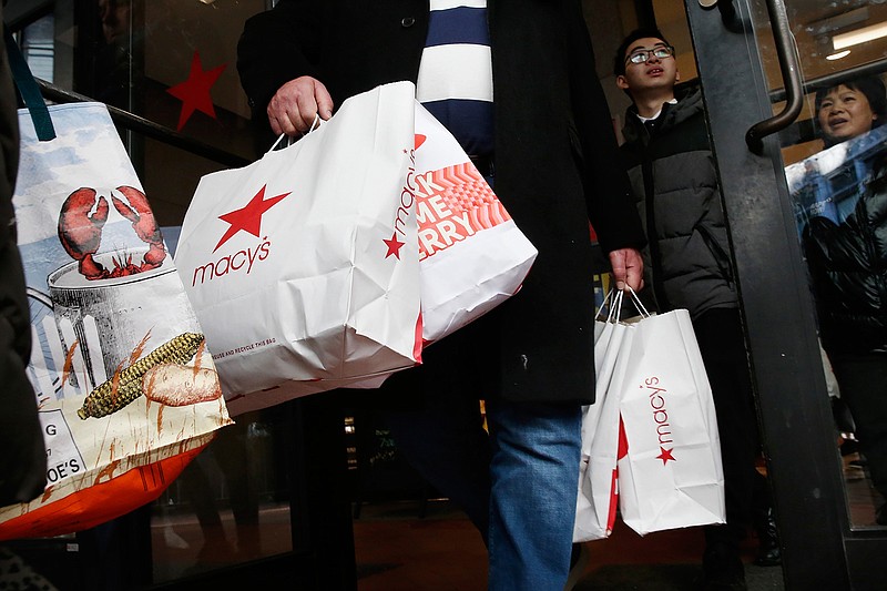 In this Friday, Nov. 29, 2019 file photo, shoppers leave Macy's in Boston. This year's Black Friday shopping event will be much different from ever before. Retailers will be enforcing social distancing, many stores will be closed on Thanksgiving Day and shoppers will be scooping up deals via their computer screens.  (AP Photo/Michael Dwyer, File)
