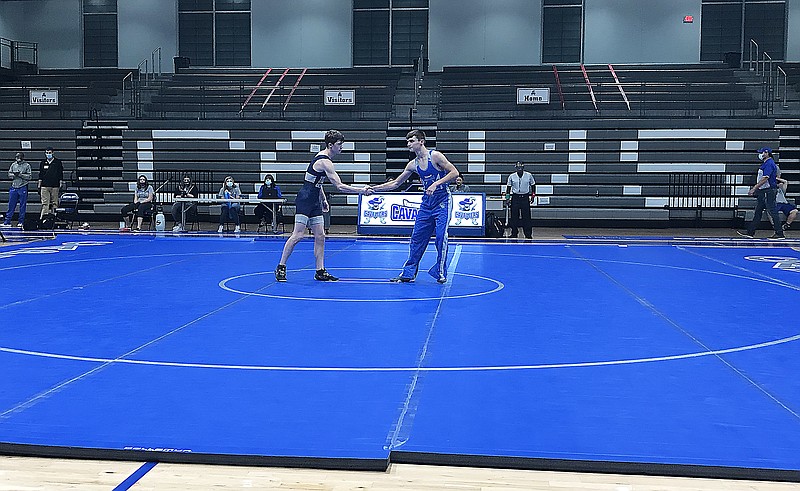 Capital City's Eli Schuemann (right) and Father Tolton's Roland Harrison shake hands during team introductions prior to the start of Friday night's wrestling dual at Capital City High School.