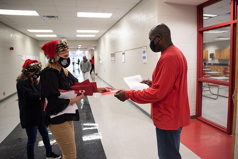 Becky Kesler, Texarkana Arkansas School District Superintendent, hands a bonus check Friday to Donald Williams, a teacher at Arkansas High School.