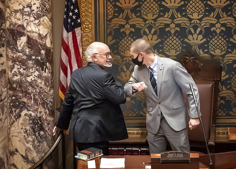 FILE - In this Nov. 12, 2020 file photo, outgoing Minnesota State Senate President Senate President Jeremy Miller, R-Winona gave Sen. David Tomassoni, DFL-Chisholm a congratulatory elbow bump before Tomassoni addressed the Senate Chamber in St. Paul, Minn.   At least 187 state legislators nationwide have tested positive for the virus and four have died since the pandemic began, according to figures compiled by The Associated Press. Twelve Arkansas lawmakers have tested positive for the virus over the past month, the second largest known outbreak in a state legislature. (Glen Stubbe/Star Tribune via AP)