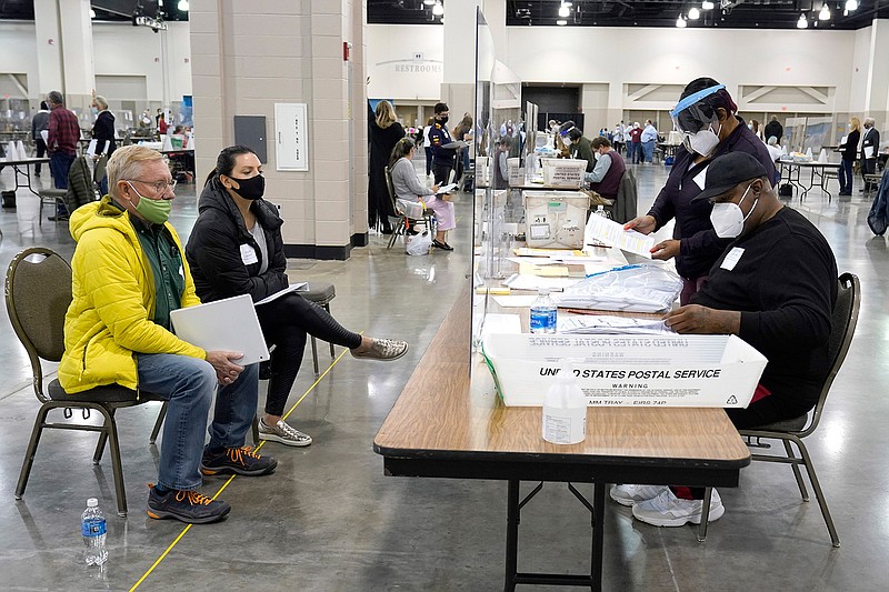 Election workers, right, verify ballots as recount observers, left, watch during a Milwaukee hand recount of presidential votes at the Wisconsin Center, Friday, Nov. 20, 2020, in Milwaukee. The recount of the presidential election in Wisconsin's two most heavily Democratic counties began Friday with President Donald Trump's campaign seeking to discard tens of thousands of absentee ballots that it alleged should not have been counted.  (AP Photo/Nam Y. Huh)