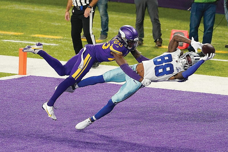 Cowboys wide receiver CeeDee Lamb catches a 4-yard touchdown pass behind Vikings cornerback Jeff Gladney during the first half of Sunday's game in Minneapolis.