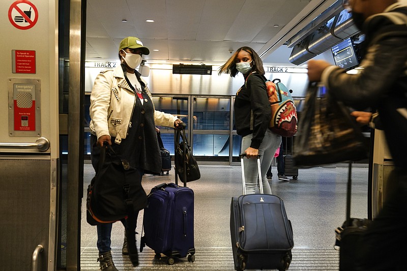 Travelers leave the AirTrain at JKF International Airport Friday, Nov. 20, 2020, in New York. Rising U.S. coronavirus cases, a new round of state lockdowns and public health guidance discouraging trips are dampening enthusiasm for what is usually the biggest travel period of the year. (AP Photo/Frank Franklin II)