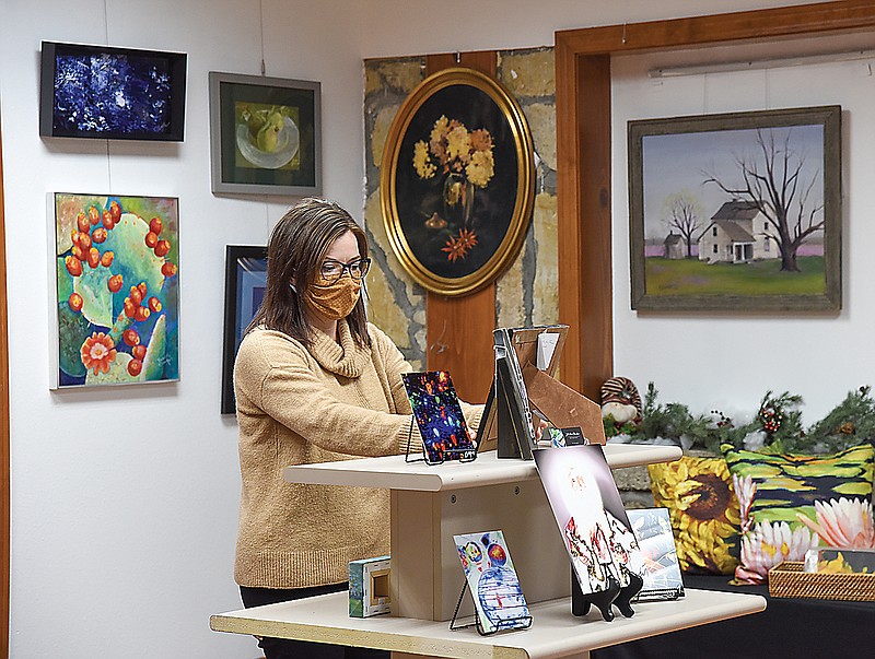 Capital Arts President Holly Nunn fixes a display at Capital Arts on Missouri Boulevard. The gallery features various kinds of art for sale from local creators.