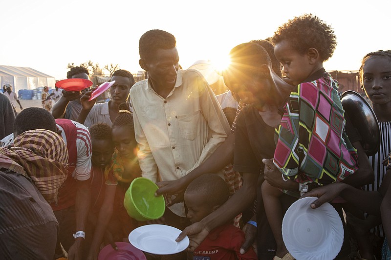 Tigray refugees who fled the conflict in Ethiopia's Tigray region, wait to get cooked rice served by Sudanese local volunteers at Um Rakuba refugee camp in Qadarif, eastern Sudan, Monday, Nov. 23, 2020. Tens of thousands of  people have fled a conflict in Ethiopia for Sudan, sometimes so quickly they had to leave family behind. There is not enough to feed them in the remote area of southern Sudan that they rushed to. (AP Photo/Nariman El-Mofty)