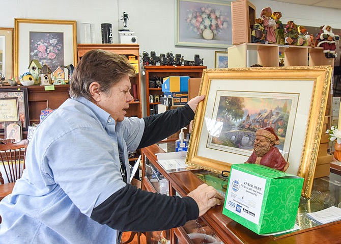 Donna Deetz, owner of Click-2-Sell-4-U, sets up a framed Thomas Kinkade print that will be given away after Saturday, the day shoppers sign up for the drawing. Deetz's shop is one of numerous downtown Jefferson City stores participating in this weekend's Small Business Saturday.