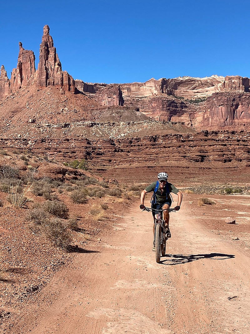 Robert Abbe rides along the White Rim Road with a tower known as the Washer Woman looming in the background. (Photo for The Washington Post by John Briley)