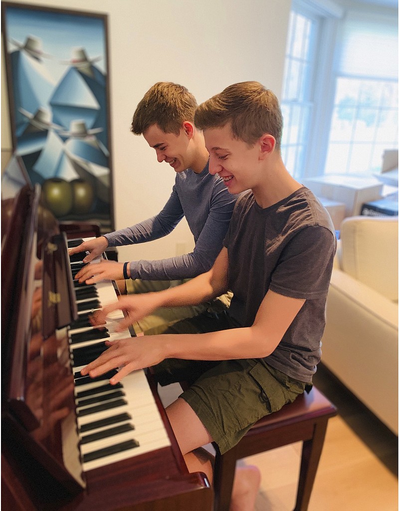 This Nov. 20, 2020 photo released by Andrea Fage shows brothers Rafael Fage, 16, background, ad Noah Fage, 14 playing the piano at their home in Harrison, N.Y. During the pandemic lockdown, private piano lessons for boys stopped. They researched movie soundtracks and learned the score on their own with the assistance of sites like YouTube. (Andrea Fage via AP)