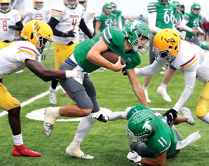 Blair Oaks quarterback Dylan Hair runs the ball between Lutheran North defensive backs Toriano Pride (left) and Elisha Thanga (right) during last Saturday's Class 3 quarterfinal game at the Falcon Athletic Complex in Wardsville.