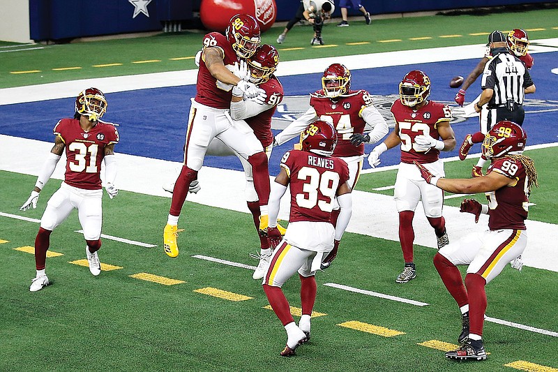 Washington Football Team's Montez Sweat (second from left) and Ryan Kerrigan celebrate Sweat's interception of a pass by Cowboys quarterback Andy Dalton that Sweat ran back for a touchdown during the second half Thursday's game in Arlington, Texas.
 