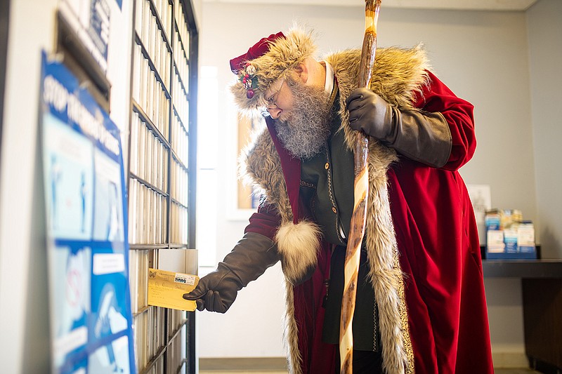 Allan McEneaney, or Santa McEneaney, pulls a letter from his P.O. box. Mc Eneaney is offering children around the world a virtual one-on-one Santa experience, where children can send letters to his P.O. box and he will arrange a short video call with the children to go over their list.