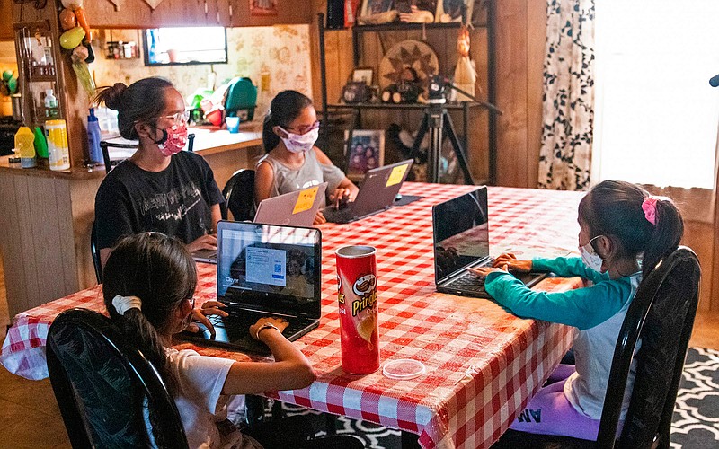 The Begaye sisters do their schoolwork at their home in Blue Gap, Ariz., on Sept. 24, 2020. Shown from left are high school senior Chenoa, fourth-grader Sonora, first-grader Annabah and second-grader Winona. On the Navajo Nation, a high school senior spends six hours most days doing homework in a car next to a school bus turned Wi-Fi hotspot. It's the only way to get assignments to teachers. COVID-19 has brought one of the greatest challenges yet to these students.   (Megan Marples/Cronkite News via AP)