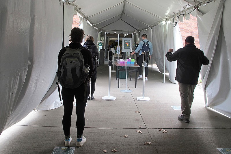 In this Nov. 12, 2020, photo, University of Vermont students walk through a tent leading to a COVID-testing site on campus in Burlington, Vt. As coronavirus cases are surging around the U.S., some colleges and universities are rethinking some of their plans for next semester. (AP Photo/Lisa Rathke)