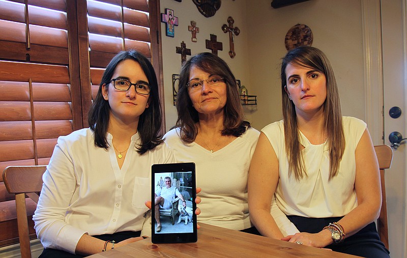 In this Feb. 15, 2019 file photo, Dennysse Vadell sits between her daughters Veronica, right, and Cristina holding a digital photograph of father and husband Tomeu who is currently jailed in Venezuela, in Katy, Texas. Tomeu Vadell, who is one of six U.S. oil executive jailed for three years in Venezuela, says in a letter from prison provided to The Associated Press on Tuesday, Nov. 24, 2020, that it's especially painful to be separated during the Thanksgiving season from from his wife, three adult children and a newborn grandson he's never held.  (AP Photo/John L Mone, File)